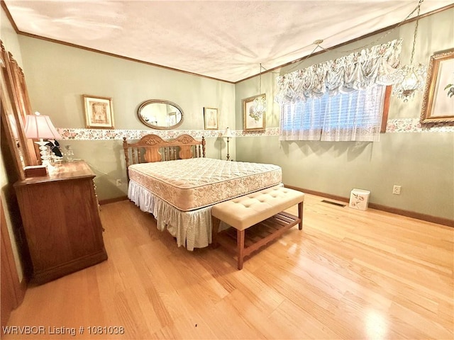 bedroom featuring crown molding, wood finished floors, and baseboards