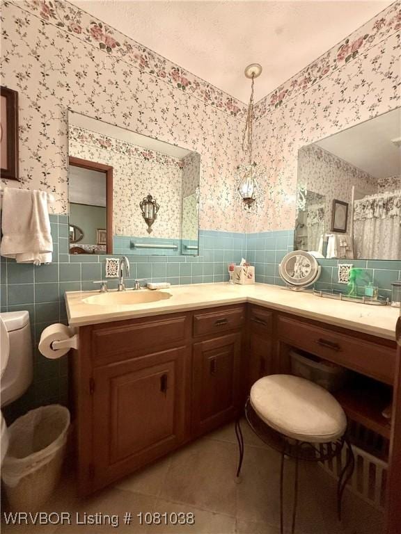 bathroom featuring wallpapered walls, tile patterned floors, tile walls, a wainscoted wall, and toilet