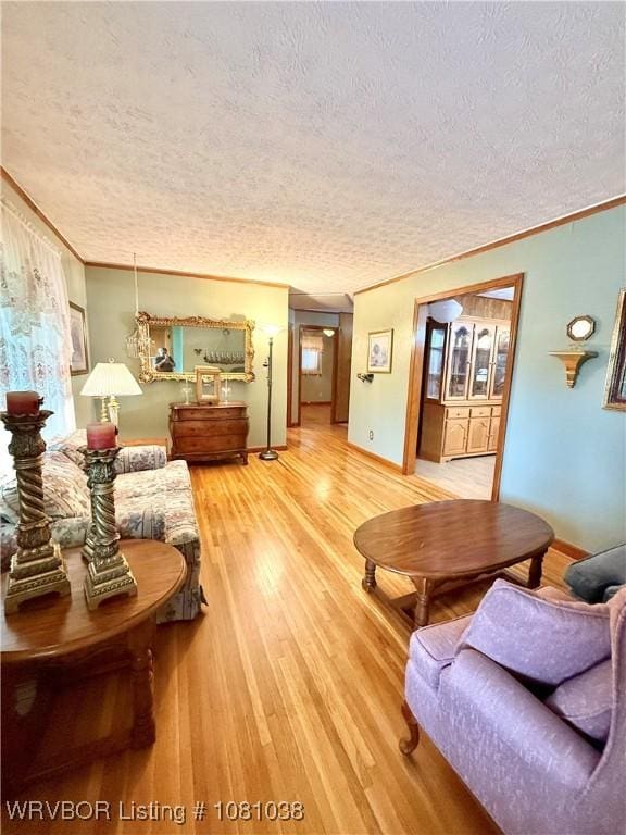 living room featuring a textured ceiling, light wood-style floors, crown molding, and baseboards