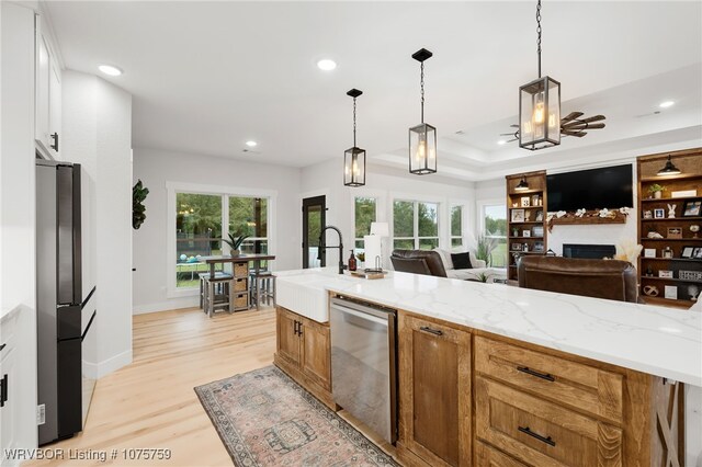 kitchen with light stone countertops, appliances with stainless steel finishes, decorative light fixtures, and white cabinetry