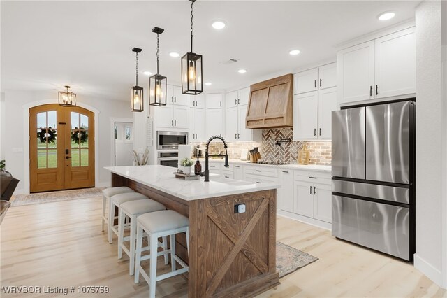 kitchen featuring white cabinets, an island with sink, and appliances with stainless steel finishes