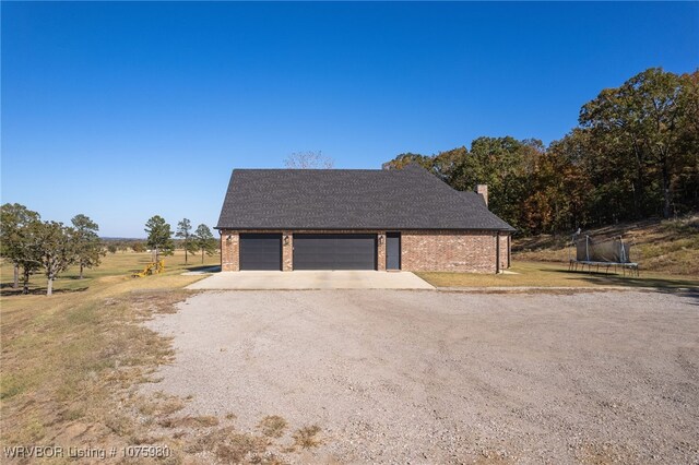 exterior space featuring a rural view, a trampoline, and a garage