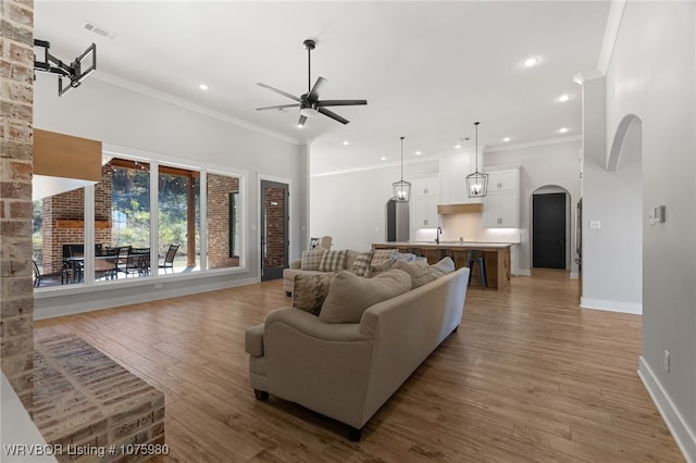 living room featuring ceiling fan, a fireplace, ornamental molding, and hardwood / wood-style flooring