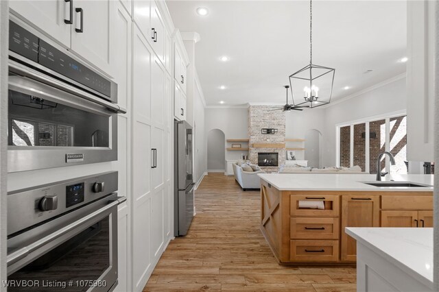 kitchen with a fireplace, stainless steel fridge, white cabinetry, and ornamental molding