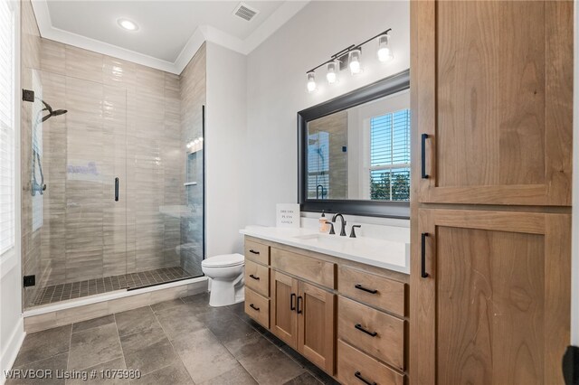 bathroom featuring toilet, vanity, a shower with shower door, and ornamental molding