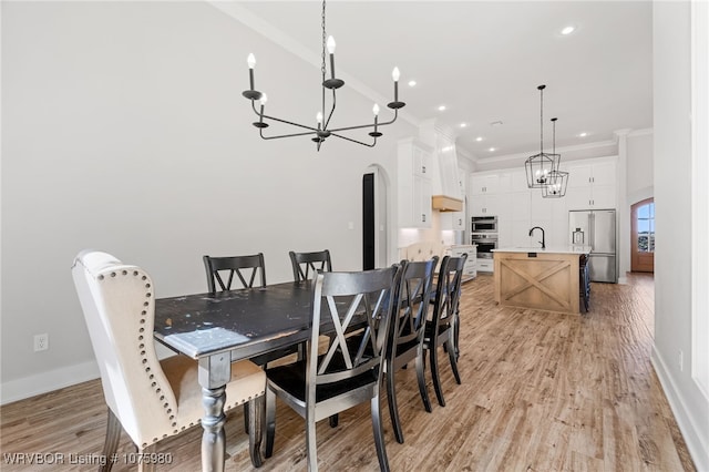 dining space featuring light hardwood / wood-style flooring, crown molding, and sink