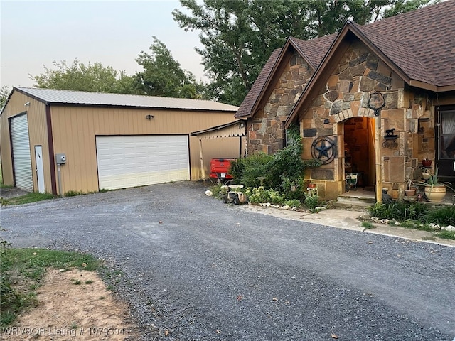 view of front of property with a garage, stone siding, and roof with shingles