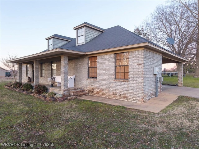 view of front facade with a patio area, concrete driveway, brick siding, and a front yard