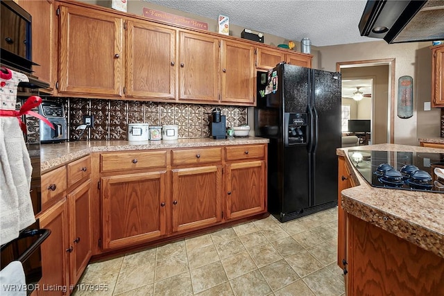 kitchen featuring black appliances, extractor fan, brown cabinetry, and light countertops