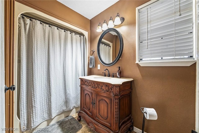 bathroom featuring a textured wall, shower / tub combo with curtain, and vanity