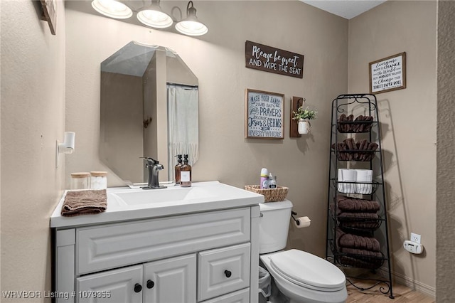 full bath with wood finished floors, vanity, and toilet