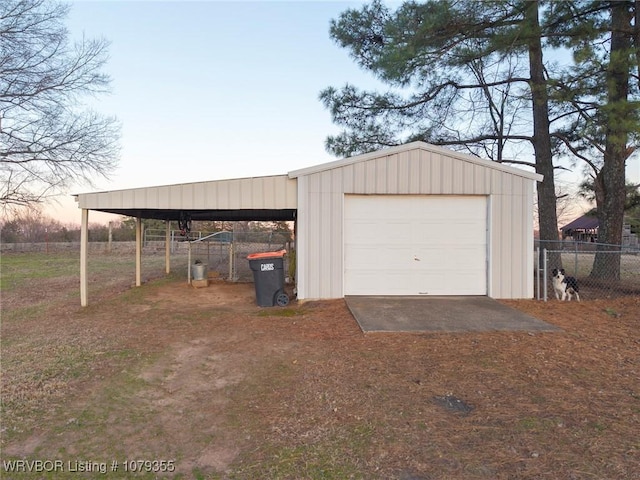 garage with dirt driveway, fence, and a detached garage