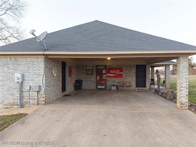 view of front of property with concrete driveway, an attached carport, roof with shingles, and brick siding