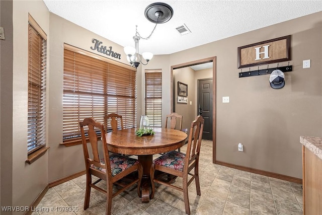 dining area with visible vents, a notable chandelier, a textured ceiling, and baseboards