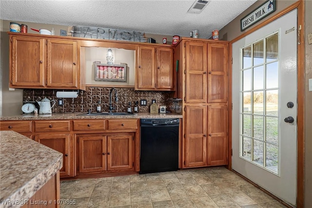 kitchen with black dishwasher, visible vents, brown cabinetry, and a sink