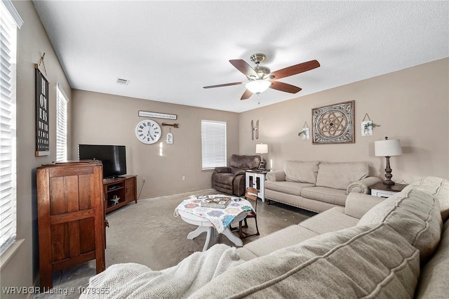 carpeted living room with a healthy amount of sunlight, ceiling fan, visible vents, and a textured ceiling