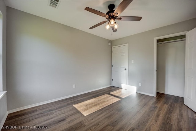 unfurnished bedroom featuring wood finished floors, baseboards, a closet, and a ceiling fan