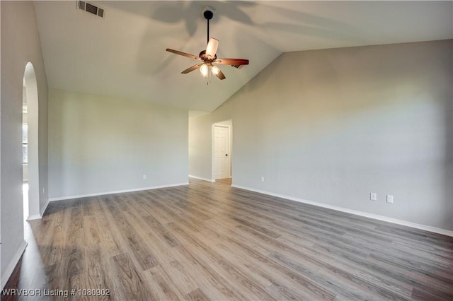 unfurnished room featuring a ceiling fan, arched walkways, wood finished floors, baseboards, and high vaulted ceiling