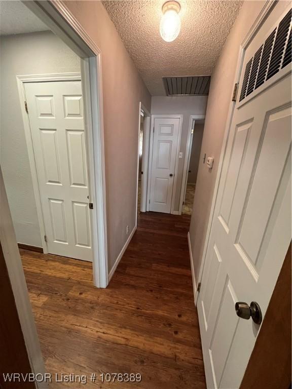 corridor featuring dark hardwood / wood-style flooring and a textured ceiling