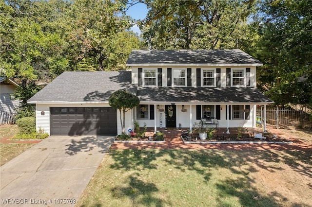 view of front of property featuring covered porch, a garage, and a front lawn