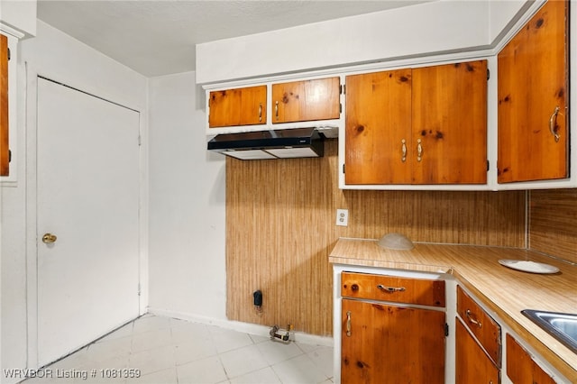 4002 57th St, Fort Smith, AR 72904 - kitchen featuring light countertops, brown cabinetry, under cabinet range hood, and light tile patterned floors