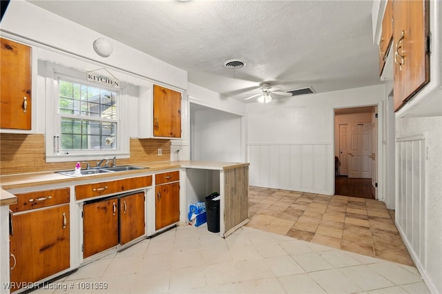 4002 57th St, Fort Smith, AR 72904 - kitchen featuring light countertops, brown cabinets, tasteful backsplash, ceiling fan, and a wainscoted wall