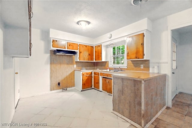4002 57th St, Fort Smith, AR 72904 - kitchen with brown cabinets, light countertops, a peninsula, decorative backsplash, and light floors