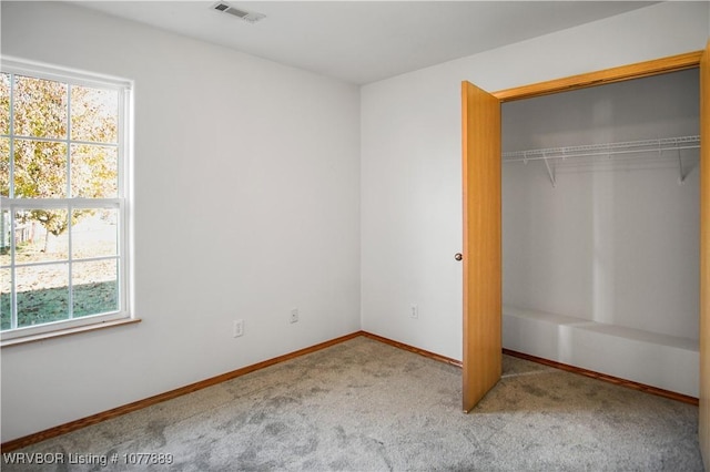 unfurnished bedroom with multiple windows, light colored carpet, and a closet