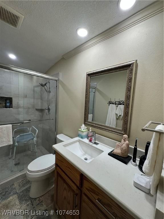 bathroom with vanity, toilet, ornamental molding, a textured ceiling, and a shower with shower door