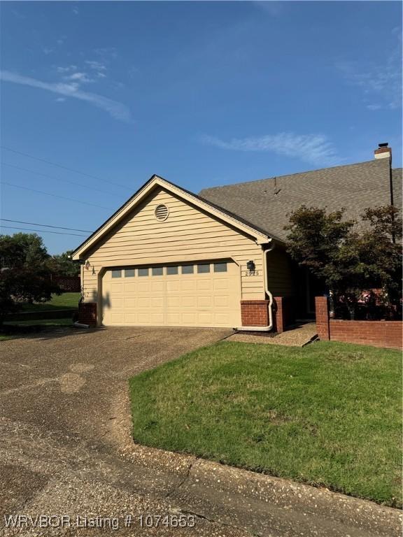 ranch-style house with a garage and a front lawn