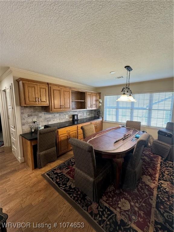 dining room with ornamental molding, a textured ceiling, and light hardwood / wood-style flooring