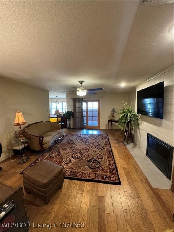 living room with ceiling fan, light hardwood / wood-style floors, and a textured ceiling