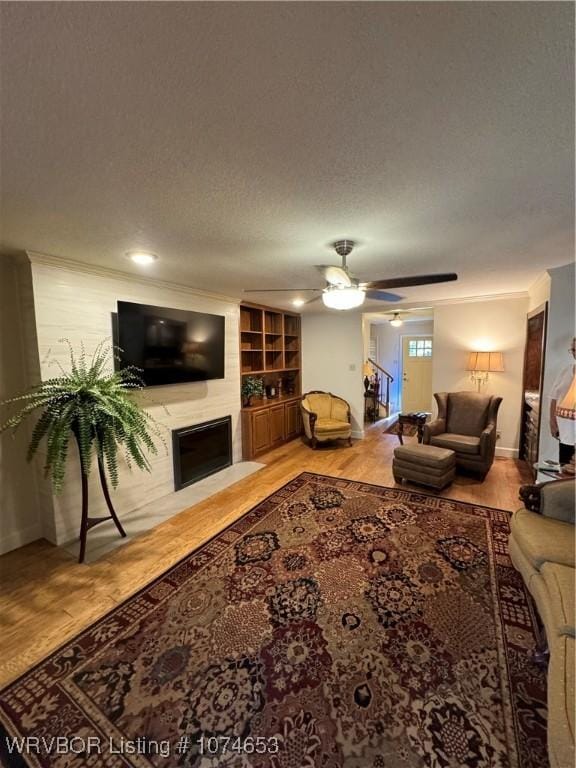 living room featuring a fireplace, hardwood / wood-style floors, a textured ceiling, and ceiling fan