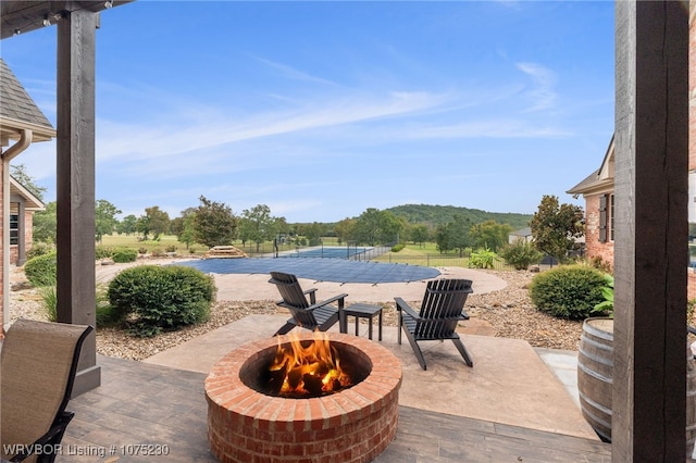 view of patio / terrace with tennis court and an outdoor fire pit