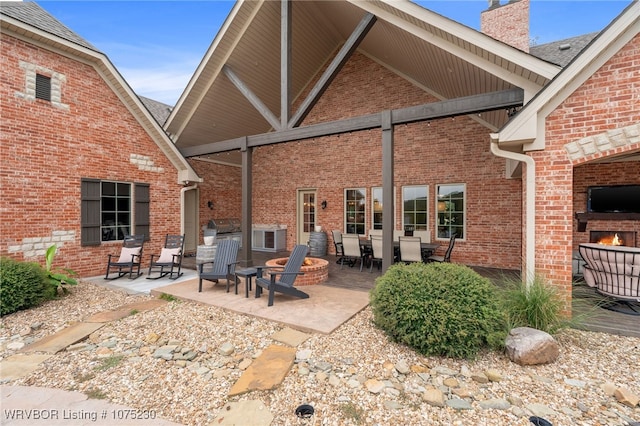 back of house with a fire pit, a fireplace, and a patio