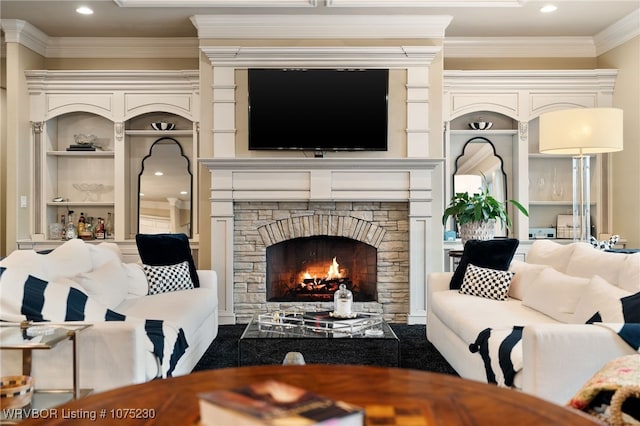 living room featuring built in features, a stone fireplace, and ornamental molding