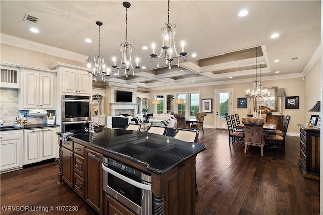 kitchen with beam ceiling, a center island, dark hardwood / wood-style floors, decorative light fixtures, and decorative backsplash