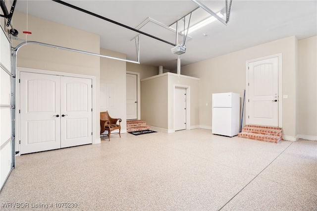 garage featuring white refrigerator and a garage door opener