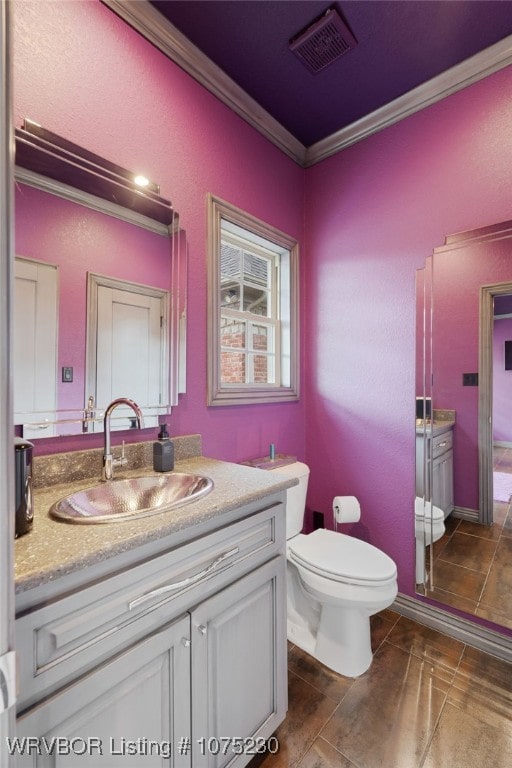 bathroom with tile patterned flooring, vanity, toilet, and crown molding