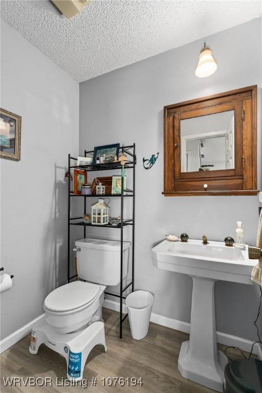 bathroom featuring hardwood / wood-style floors, toilet, and a textured ceiling