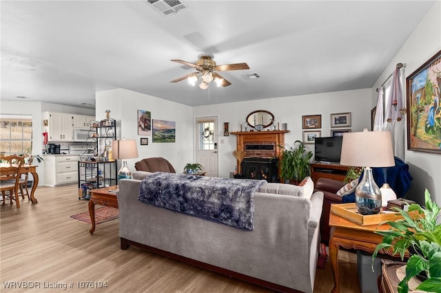 living room featuring a fireplace, light hardwood / wood-style flooring, and ceiling fan