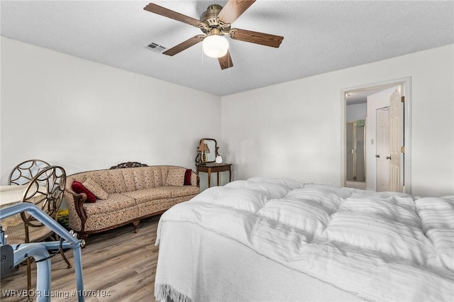 bedroom with a textured ceiling, hardwood / wood-style flooring, and ceiling fan