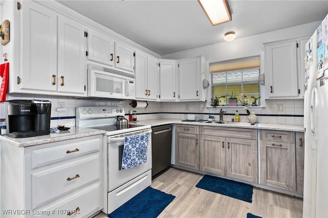 kitchen featuring white cabinets, light stone counters, white appliances, and sink