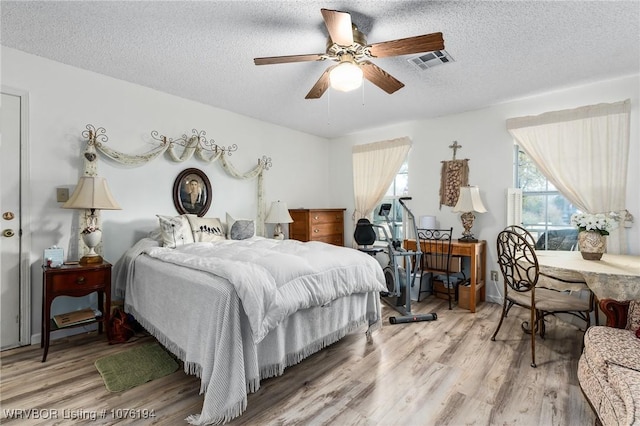 bedroom featuring ceiling fan, hardwood / wood-style floors, and a textured ceiling