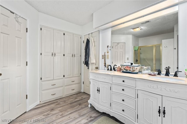 bathroom with wood-type flooring, vanity, and a shower with door