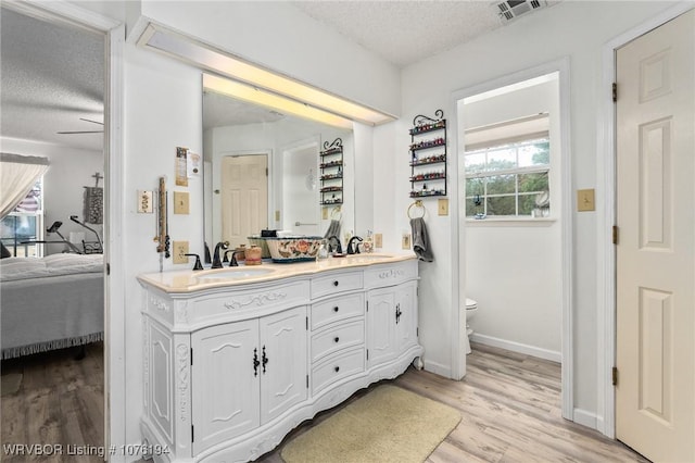 bathroom featuring vanity, a textured ceiling, ceiling fan, hardwood / wood-style floors, and toilet