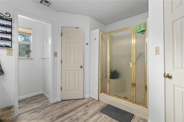 bathroom featuring hardwood / wood-style flooring, a shower with shower door, and a textured ceiling