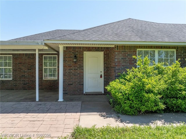 24401 Brazil Creek Loop, Shady Point, OK 74956 - view of exterior entry with brick siding and a shingled roof