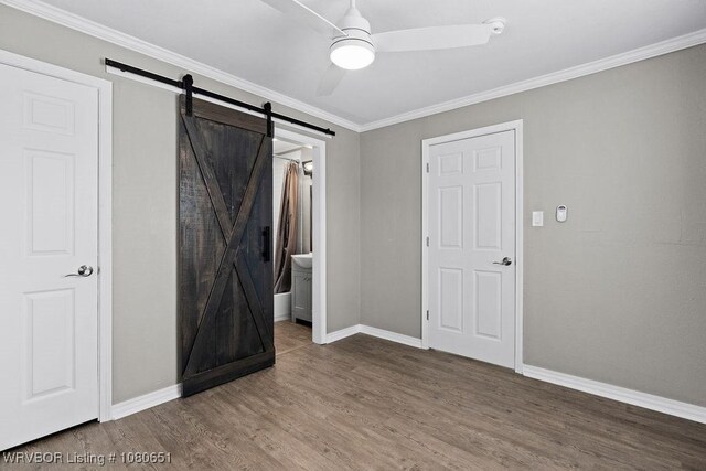 11 N 13th St, Van Buren, AR 72956 - unfurnished bedroom featuring baseboards, ornamental molding, a barn door, and wood finished floors