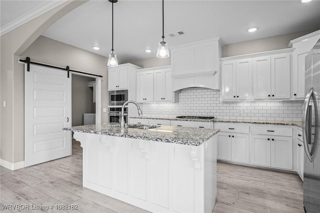 9505 Harmony Ridge Rd, Fort Smith, AR 72916 - kitchen with a barn door, stainless steel appliances, light stone counters, white cabinets, and recessed lighting